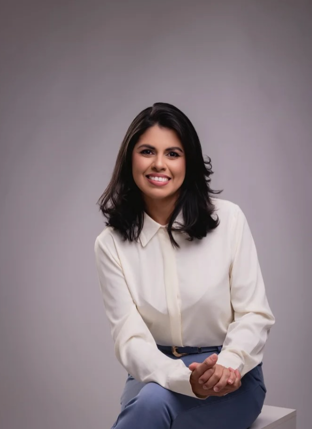 Layse Dias de camisa clara, sentada e sorrindo